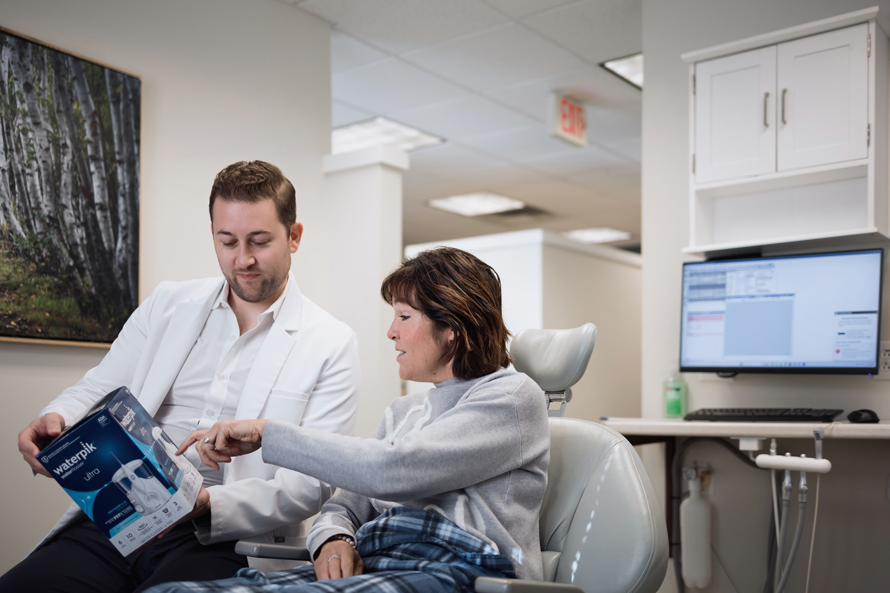 Dentist showing Waterpik to patient